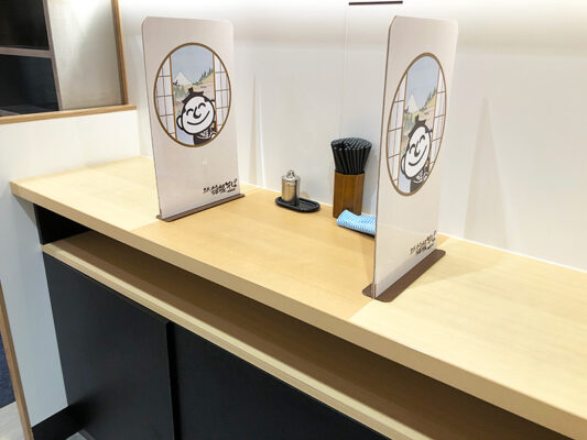 立ち食いスペースも仕切り板。箱そばのやっこさんが覗いてるイラストかわいいなー